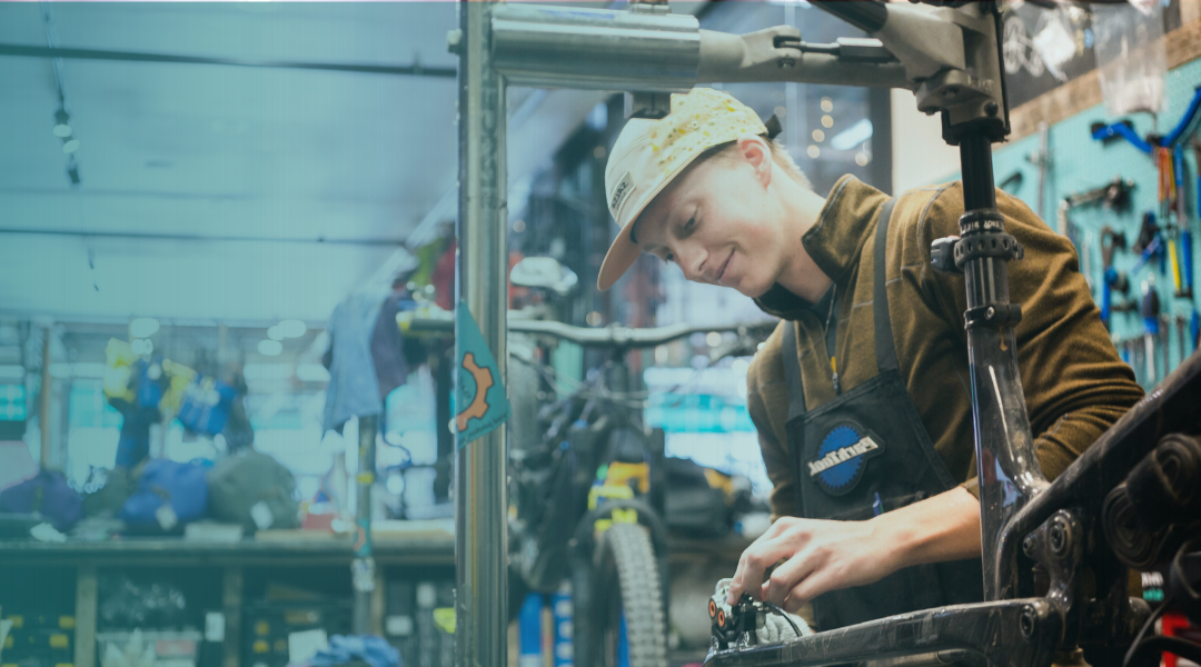 Person working on a mountain bike repair in a workshop setting