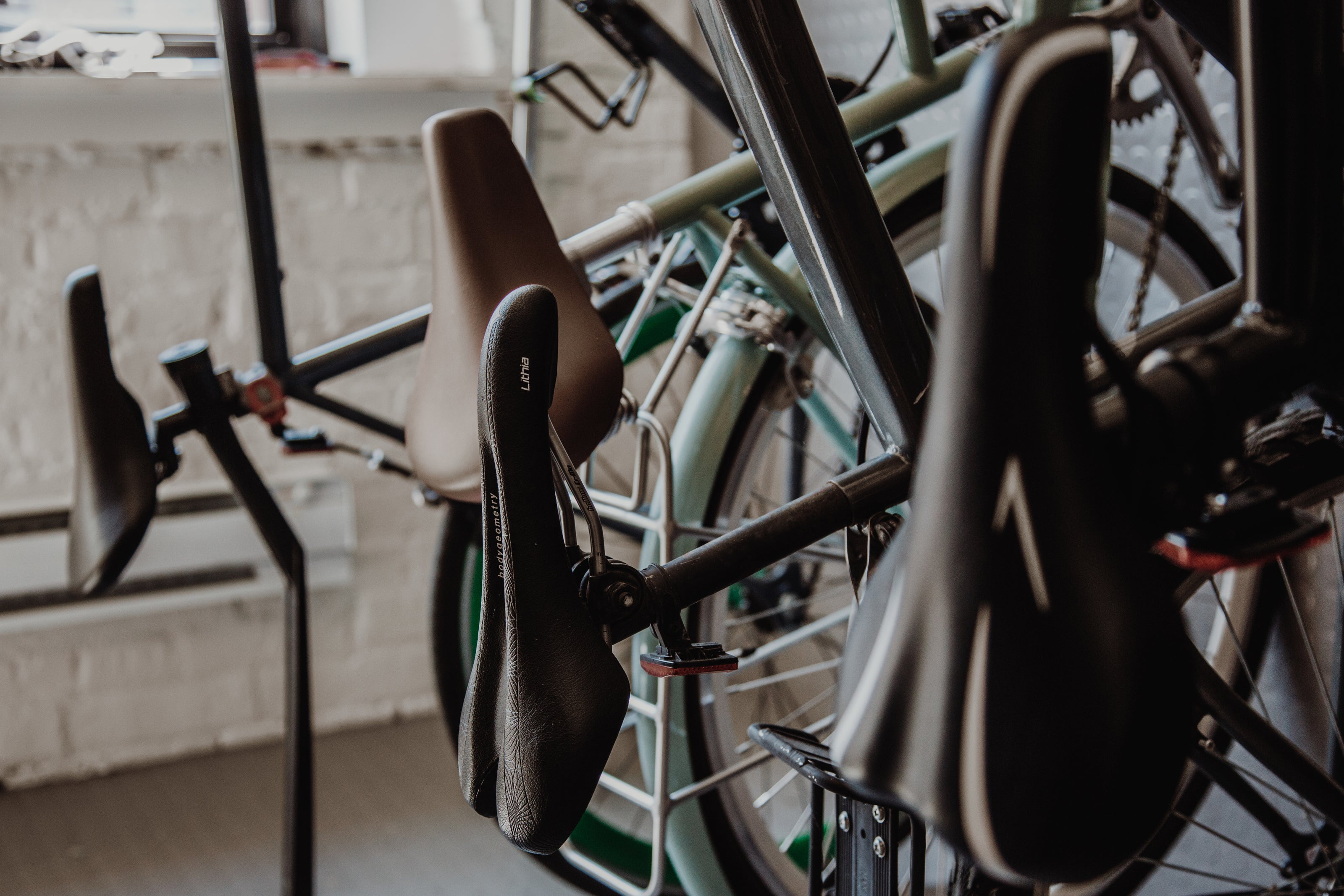 Four bikes hang on a wall stand, focusing on the bike seats.