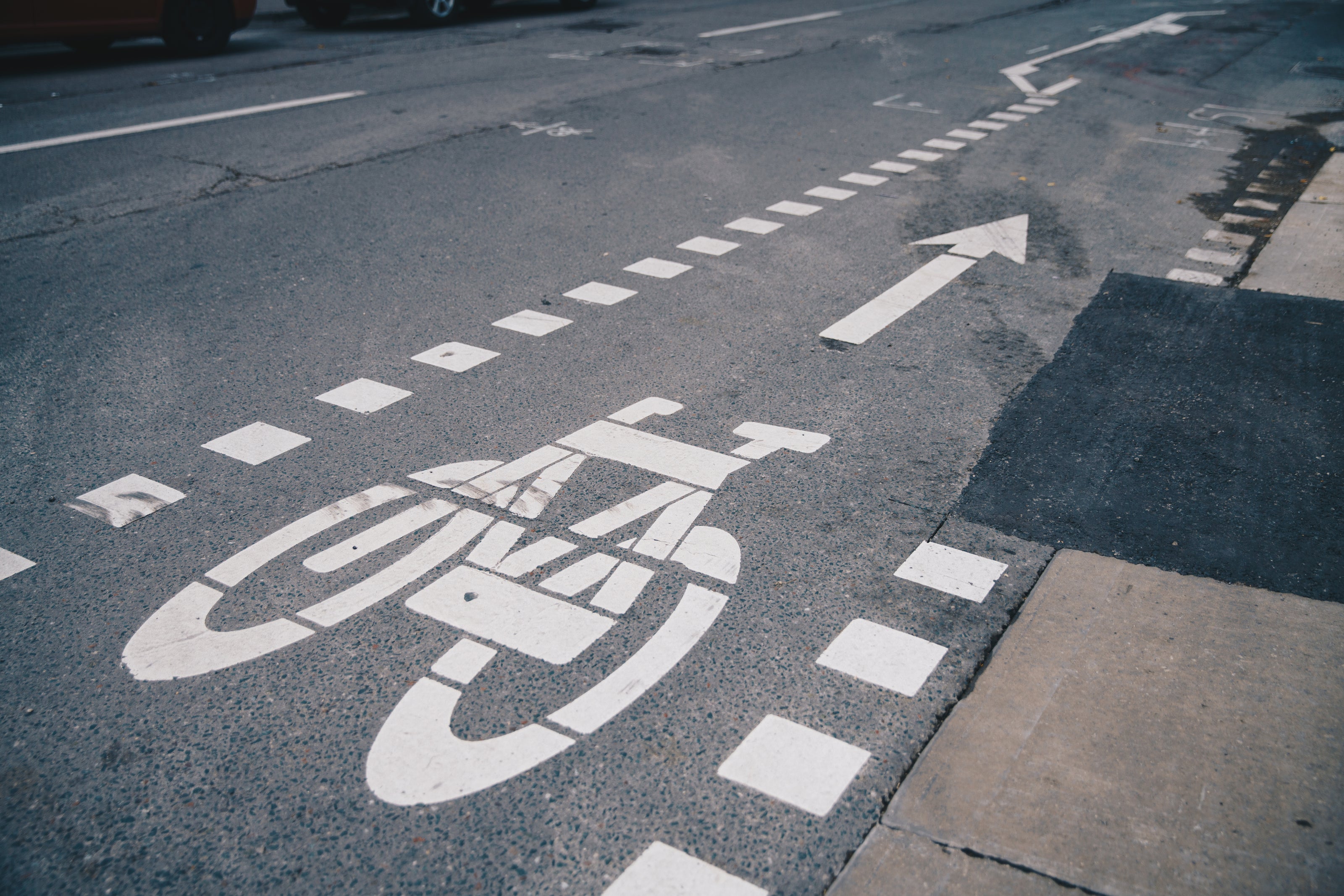 A bike lane on a road with a directional arrow pointing forward.